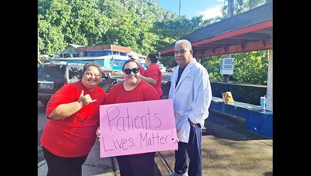 Nurses with sign as doctor looks on