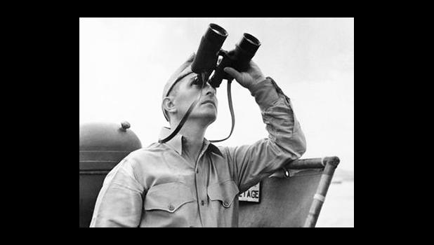 This October 1942 file photo shows Eugene Burns, Associated Press war correspondent with the Pacific Fleet, on the deck of a Navy vessel with binoculars raised as he covered operations of a task force in the South Pacific. On Dec. 7, 1941, as Japanese bombs rained down on Pearl Harbor, Burns, Associated Press chief of bureau in Honolulu, was unable to get out the urgent news of the historic attack that would draw the U.S. into World War II. The military had already taken control of all communication lines, so Burns was left without a line to the outside world. (AP Photo) This October 1942 file photo shows Eugene Burns, Associated Press war correspondent with the Pacific Fleet, on the deck of a Navy vessel with binoculars raised as he covered operations of a task force in the South Pacific. On Dec. 7, 1941, as Japanese bombs rained down on Pearl Harbor, Burns, Associated Press chief of bureau in Honolulu, was unable to get out the urgent news of the historic attack that would draw the U.S. into World War II. The military had already taken control of all communication lines,