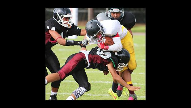 Wildcats Joseph Mauga gets hit hard by a Warrior defender during the opening half of their JV match up last Friday evening – the Wildcats collected their first win of the season over the Warriors 14 - 12. [photo: TG]
