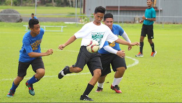 A Leone Lions’ player looks to clear the ball against two Fa’asao-Marist Crusaders defenders during an ASHSAA Boys’ JV soccer game on Monday, March 26, 2018 at Pago Park Soccer Stadium.  [FFAS MEDIA/Brian Vitolio]