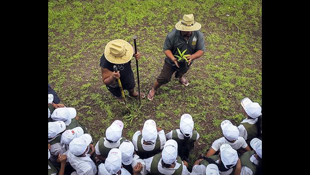 ASCC-ACNR Forestry staff (left) Galutau Aga and Tony Maugalei demonstrate proper tree planting techniques to Fagalii Elementary School students during the Forestry Program 2018 Review. [Courtesy photo]
