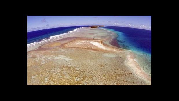 In this Nov. 5, 2015 file, aerial photo a small uninhabited island that has slipped beneath the water line only showing a small pile of rocks at low tide on Majuro Atoll in the Marshall Islands. To small island nations where the land juts just above the rising seas, the U.S. pulling out of the Paris global warming pact makes the future seem as fragile and built on hope as a sand castle. [AP file photo]