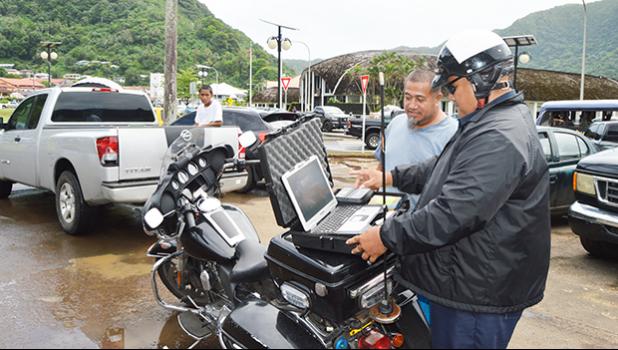 WELCOME TO THE 21ST CENTURY: Police senior officer, Lomu Mosese (left), demonstrated yesterday for a motorist, the Department of Public Safety’s new “electronic citation” or e-Ticket system, in which a police officer uses a laptop to issue a traffic violation ticket to a driver and the citation is automatically transmitted to the District Court. [photo: AF]