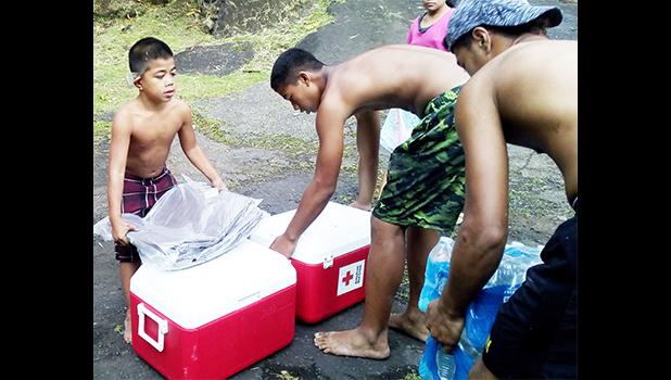Members of a family in Fagasa, who lost their home to a fire on Aug. 30th, taking coolers packed with emergency supplies and cases of bottled water and other necessities from the local American Red Cross office.  [photo: local Red Cross]
