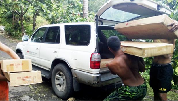 Members of a family in Fagasa, who lost their home in an Aug. 30th fire, carry out of a local American Red Cross vehicle, packages of emergency supplies from the Red Cross. Supplies included folding cots and clean up kits.  [photo: local Red Cross]