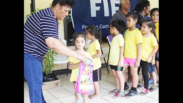 A young participant of the 2017 FFAS Summer Youth League receives her bag filled with school supplies from FFAS executive committee member Saili Ott on July 15 at Pago Park Soccer Stadium. [FFAS MEDIA/Brian Vitolio] 