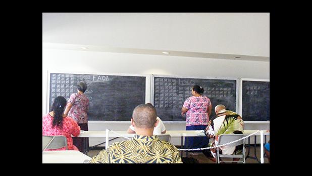 Two Election Office personnel on the chalkboard marking off one-by-one each ballot called out by a senior election official during the counting yesterday of the gubernatorial race absentee ballot at the Election Office.  [photo: FS]