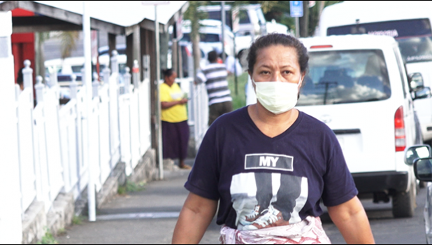 A woman walking on the street in Apia wearing a mask