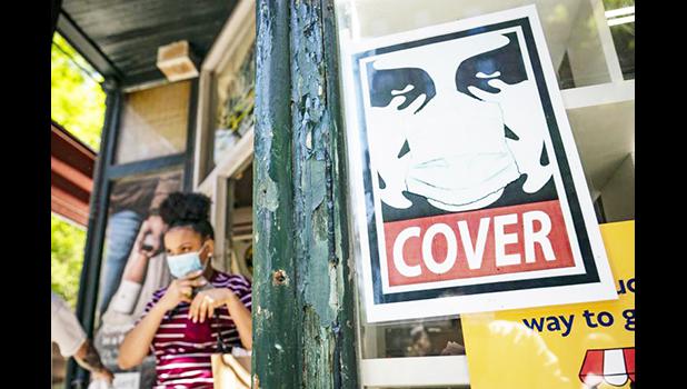 Young woman with mask near masking sign.