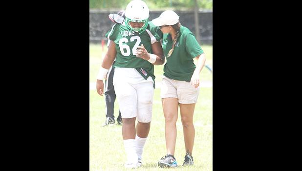 ASHSAA ATC Florence Wasko walking an injured Leone player off the field for a check up, during a time out in the second half of Leone and Nu’uuli’s varsity match up last Saturday afternoon.  [photo: TG]