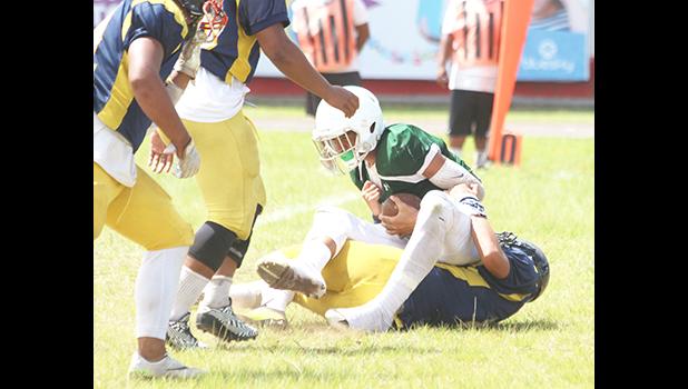 Iverson Ta’ase of Leone is stopped immediately in the backfield by Branson Pualau of Nu’uuli during the second quarter of their varsity match last Saturday. Ta’ase and the Lions won 32-0.  [photo: TG]