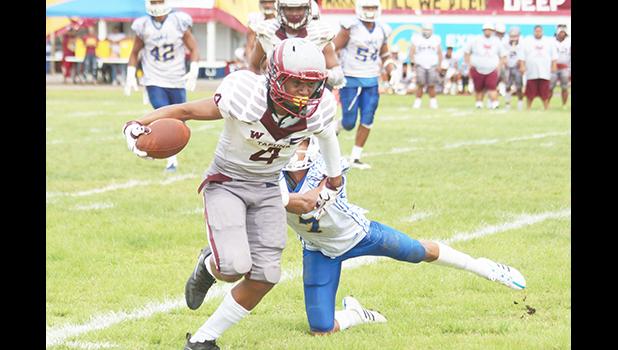Paea Latu of the Warriors trying to break a tackle by Elliot Lelei during their varsity title game last Saturday morning, where the Warriors lost to Samoana 6-7. [photo: TG]