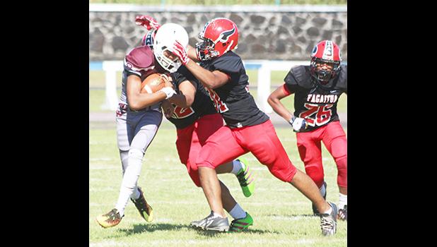 Warriors quarterback Francisco Mauigoa being devoured by two of Faga’itua’s most vicious defensive fronts, during the opening half of the JV game last Saturday.  [photo: TG]