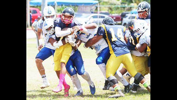 The playmaker for the Wildcats, Iosefa Mauga is stopped immediately by a host of Samoana Sharks behind the line of scrimmage for a loss during the third quarter of their varsity match up last Saturday morning. Samoana’s defensive unit shut out the Wildcats completely in a 49-0 victory, the first team to ever shut out Nu’uuli this regular season.  [photo: TG]