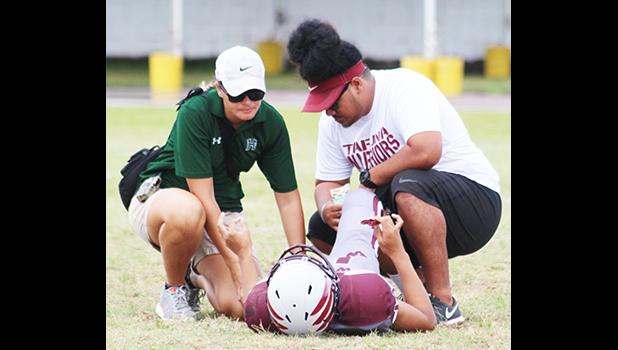 An injured Tafuna Warrior being tended to by ATC Florence Wasko and Warriors assistant coach Travis Pavihi during the opening quarter of the Warriors vs. Sharks JV match up last Saturday morning.  [photo: TG]