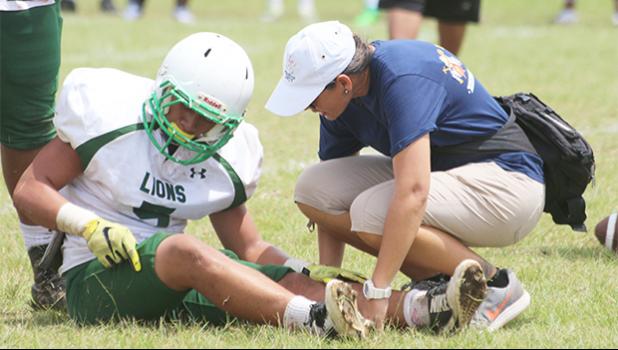 ASHSAA ATC Florence Wasko tending to an injured Leone Lion, during the second quarter of a Junior Varsity game against the Warriors last Saturday morning. Tafuna won 34-22. [photo: TG]