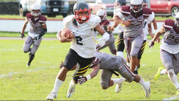  Halloween Alosio of the Wildcats running out to the sidelines, trying to evade a tackle from a Warrior defender during the first quarter of a junior varsity game last Friday evening – Tafuna defeated Nu’uuli 24-8. [photo: TG]