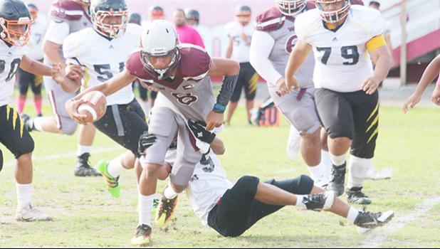 Francisco Mauigoa trying to break a tackle, as he is swamped by Nu’uuli defenders at midfield, after Mauigoa tucked and ran the ball for yardage.  [photo: TG]