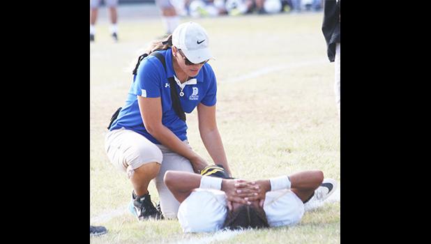 ASHSAA ATC Florence Wasko tends to an injured Nu’uuli Wildcat on the field during a Junior Varsity game against the Tafuna Warriors last Friday evening.  [photo: TG]