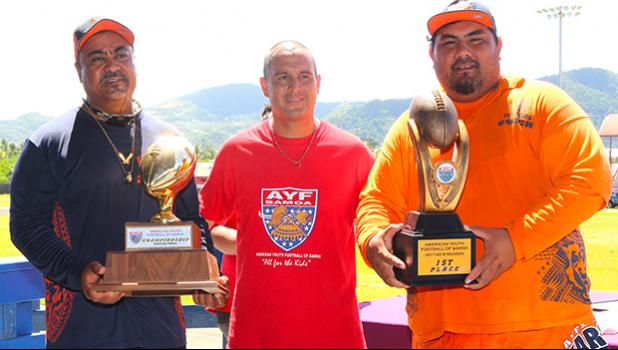 AYFS Bears Head Coach Sa Suluai with his Offensive Coordinator Keith Leuta receiving the AYFS Perpetual Trophy for the third time, along with the 1st Place trophy for being ‘Back-2-Back’ Undefeated Champs during the awards ceremony last Saturday. Also pictured is AYFS President Victor Avalos. [photo: TG]
