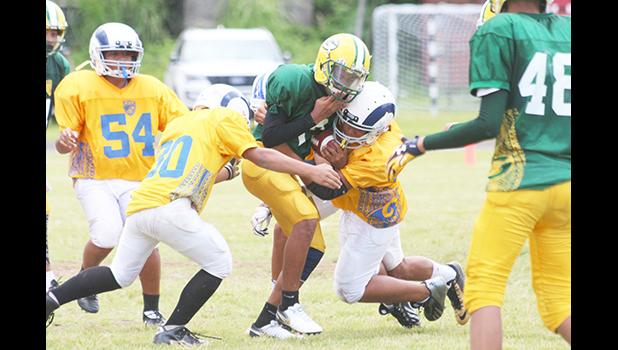 Running Back for the the AYFS Packers ‘Ricky’ getting sandwiched by two AYFS Rams defenders during the season opener last Saturday at the Veterans Memorial Stadium. The Rams claimed their first victory of the season with a 8-6 win. [photo: TG]