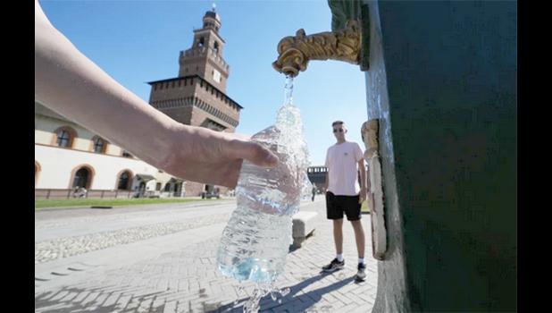 Tourists fill plastic bottles with water from a public fountain at the Sforzesco Castle, in Milan, Italy, June 25, 2022. (AP Photo/Luca Bruno) filling a plastic water bottle