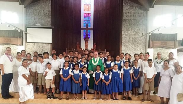 Several students and faculty members of St. Theresa Elementary School surround Bishop Peter Brown