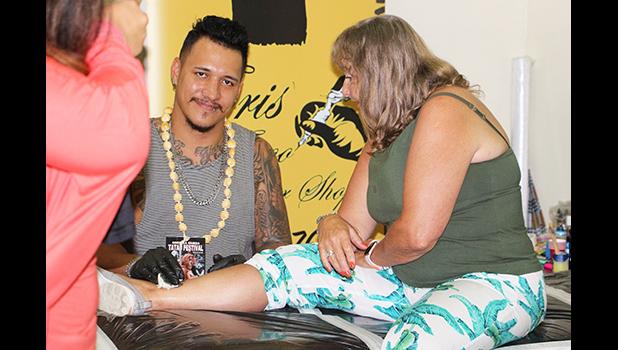 Christopher Adolfo Krieg smiles for the Samoa News Camera while tattooing a tourist