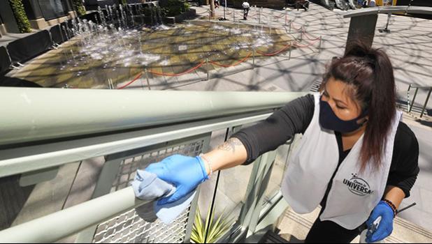 In this Thursday, June 11, 2020 file photo, Andrea Castaneda cleans the railings at Universal CityWalk near Universal City, Calif. On Friday, June 12, 2020, the Centers for Disease Control and Prevention posted guidelines to reduce the risk of COVID-19 coronavirus infection, along with a set of “considerations” for organizing and attending mass gatherings, as people emerge from stay-at-home lock downs and attempting some semblance of normal life. (AP Photo/Mark J. Terrill) Woman cleaning a stair railing