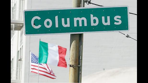 Street sign that says Columbus with flags in background
