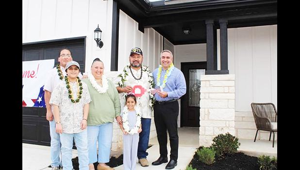 Taetuli and family in front of their new home.