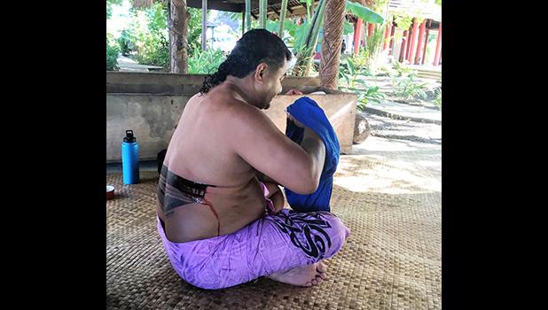 A schoolteacher in the midst of receiving a full pe'a