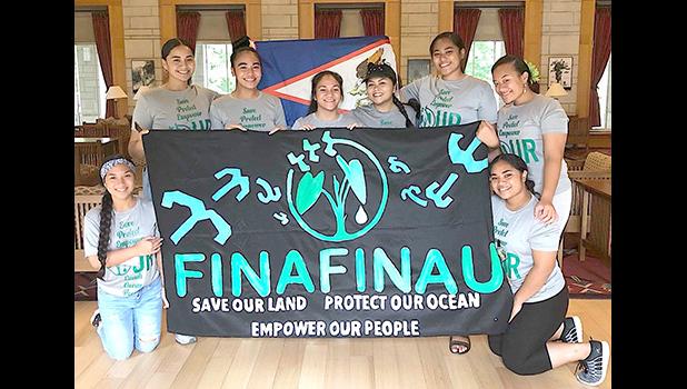 Finafinau members with sign saying save our land, protect our ocean, empower our people