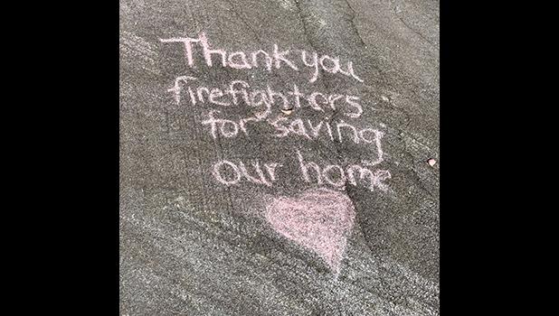 thank you message chalked on the driveway of a home that was spared.