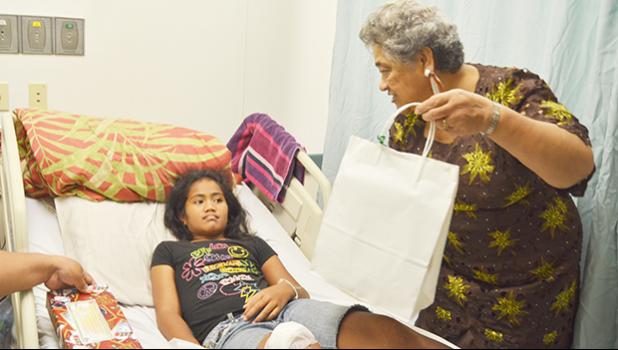 First Lady, Cynthia Moliga presenting a gift to a young girl at the Pediatric Ward at LBJ hospital yesterday during the Governor’s annual visit for the holiday season. [photo by AF]
