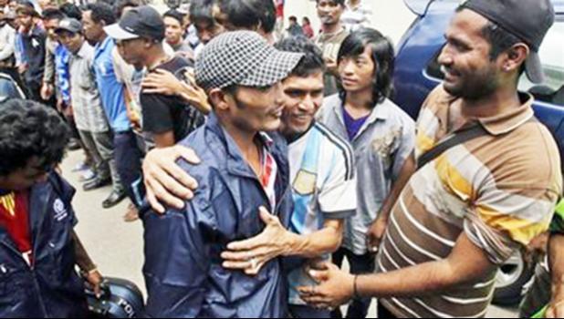 In this Sept. 8, 2015 photo, a Burmese fisherman, center, is embraced by a friend as he leaves the port town of Ambon, Maluku province, Indonesia. More than 2,000 fishermen have been rescued this year from brutal conditions at sea, their freedom prompted by an Associated Press investigation into seafood brought to the U.S. from a slave island in eastern Indonesia. Dozens of Burmese men in the bustling port town of Ambon were the latest to go home, some more than a decade after being trafficked onto Thai tra