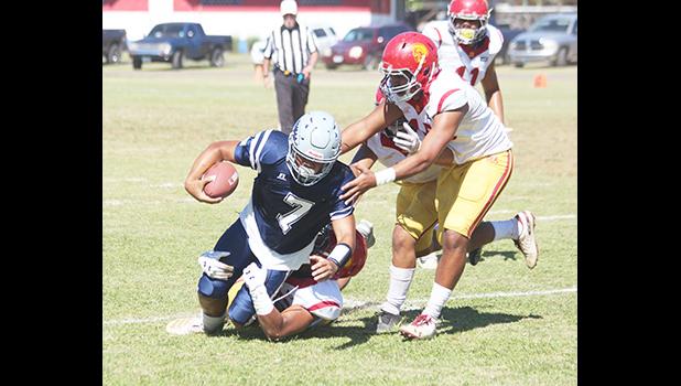 Samoana Sharks quarterback Viliamu Tanielu is brought down by three Tafuna Warrior defenders