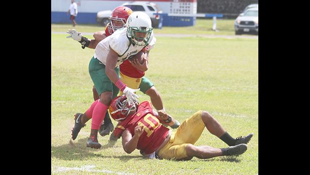 A Leone Lion defender tries to break away from two Tafuna Warriors