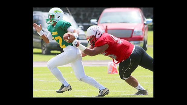 Leone's quarterback Ronnie Ma'ae, trying to escape the wrath of Faga'itua's Blessman Ta'ala in the second quarter of their game – Ta’ala sacked Ma’ae for a huge loss. [photo: TG]