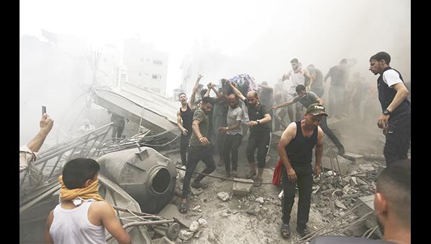 Palestinians remove a dead body from the rubble of a building after an Israeli airstrike