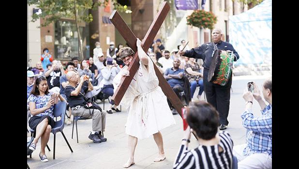 Actor Timothy Watkins carries a cross during his portrayal of Jesus Christ in a reenactment of the Journey to the Cross in Sydney, Australia, Friday, April 2, 2021, during Good Friday observance. Christians around the world are marking the death of Jesus Christ ahead of Easter Sunday. (AP Photo/Rick Rycroft) Actor Timothy Watkins carries a cross
