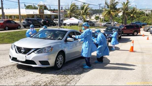 Car at a Covid-19 testing point in Guam with medical people standing by.