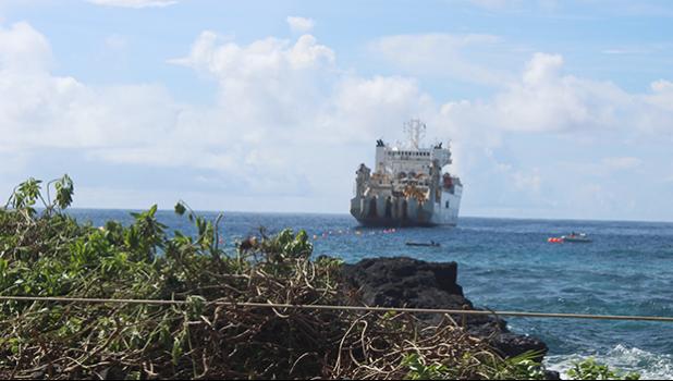 This Samoa News photo on Saturday morning, Apr. 21, 2018, shows the vessel, CS Responder, laying the undersea fiber optical cable for Hawaiki Submarine Cable LP, anchored off Fogagogo. Crew on two small boats are seen on the ocean, as VIPs and guests gathered on Fogagogo the high rocky shoreline area - close to the airport runway - to witness the Hawaiki cable landing.  [photo: FS]