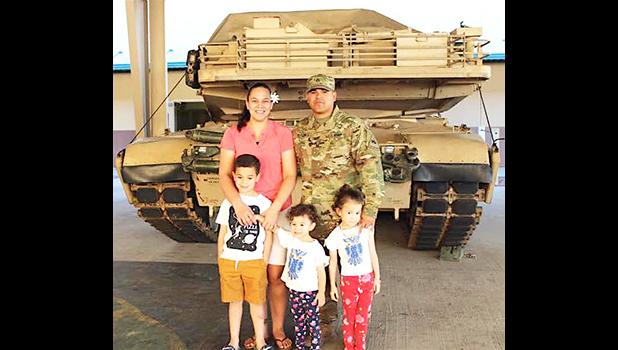 DeAngelo Herrera and family posing in front of a tank