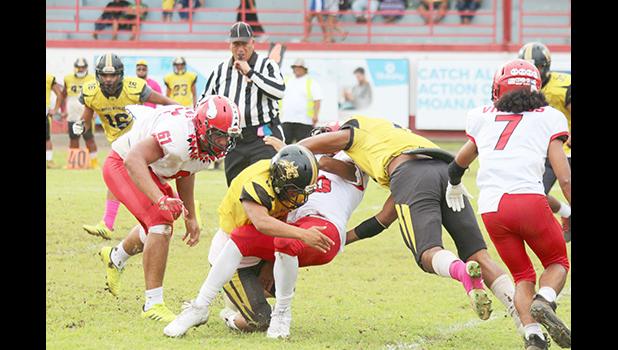 Faga'itua Vikings ball carrier Roy Ulugalu is tackled by two Nu’uuli Wildcat defenders 