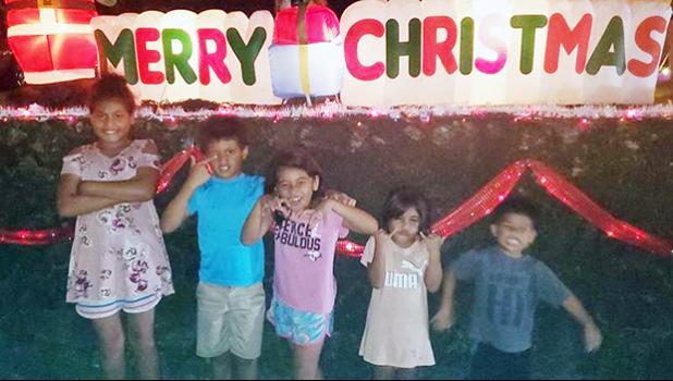 The Uelese siblings in front of a Merry Christmas display in Aoloau