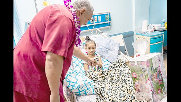 Gov. Lemanu P.S. Mauga delivering gift to a child patient at LBJ