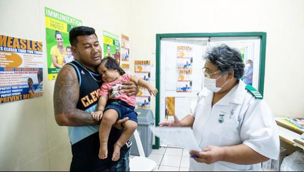 Nurse Fa'atafa Tavita (R) speaking with a father holding his child at the Apia Town Clinic