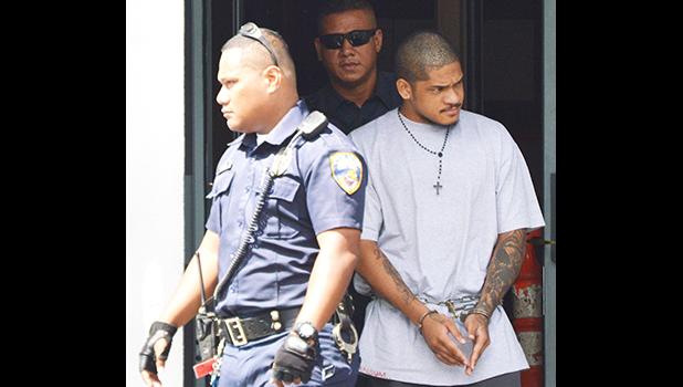 Manu Lefatia in handcuffs escorted by two police officers