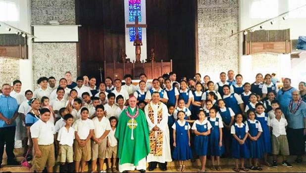 Most Reverend Bishop Peter Hugh Brown (front, center) who is pictured with St. Theresa Elementary School chaplain, Reverend Father Kolio Etuale; St. Theresa Elementary School principal Victor Langkilde (far left), staff members and students.